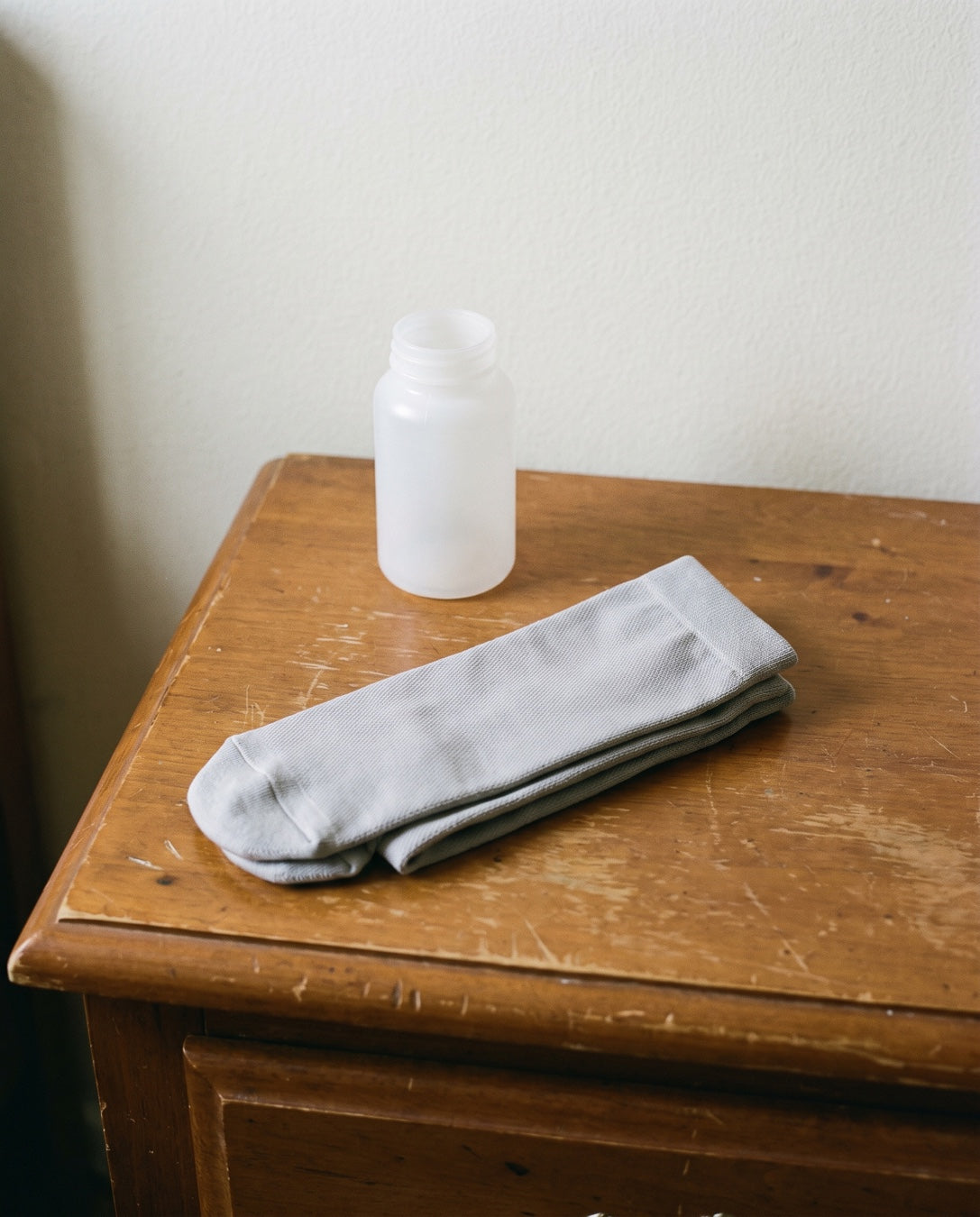 The socks folded in front of a plain pill bottle on a nightstand