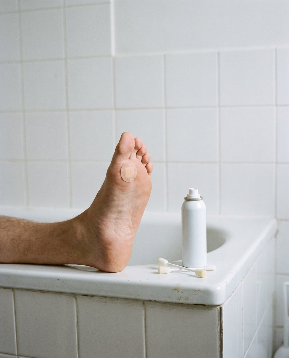 A foot on the edge of a bath with a home freeze spray beside it