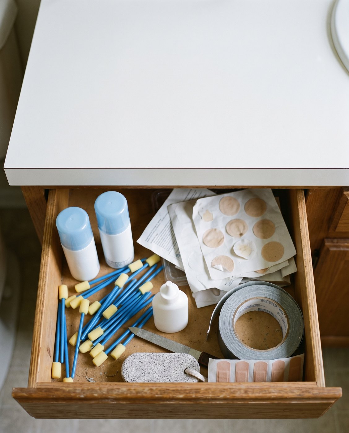 An open drawer holding treatment bottles, applicators, pads, and tape.