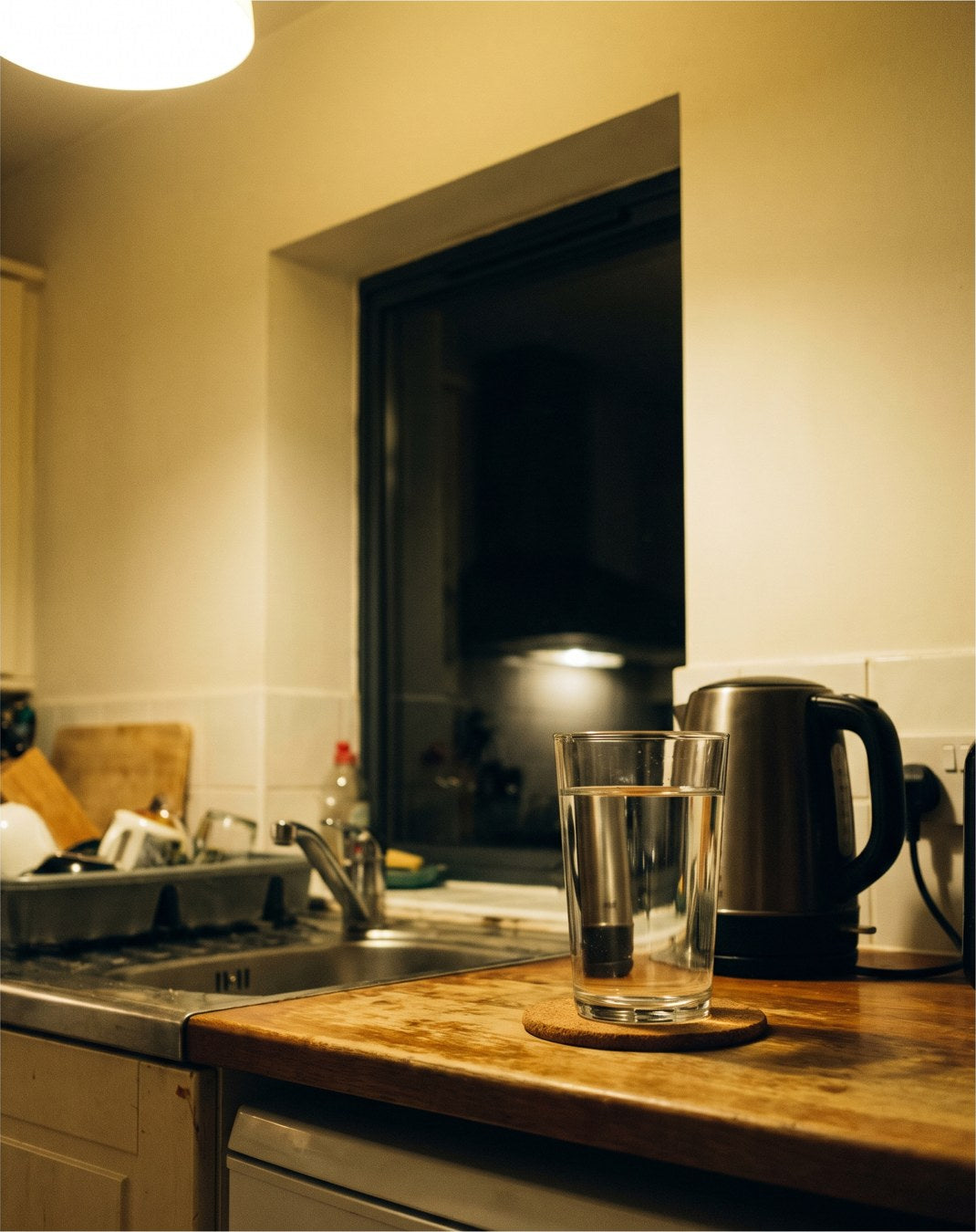 A full glass of water left untouched on a kitchen counter in the evening